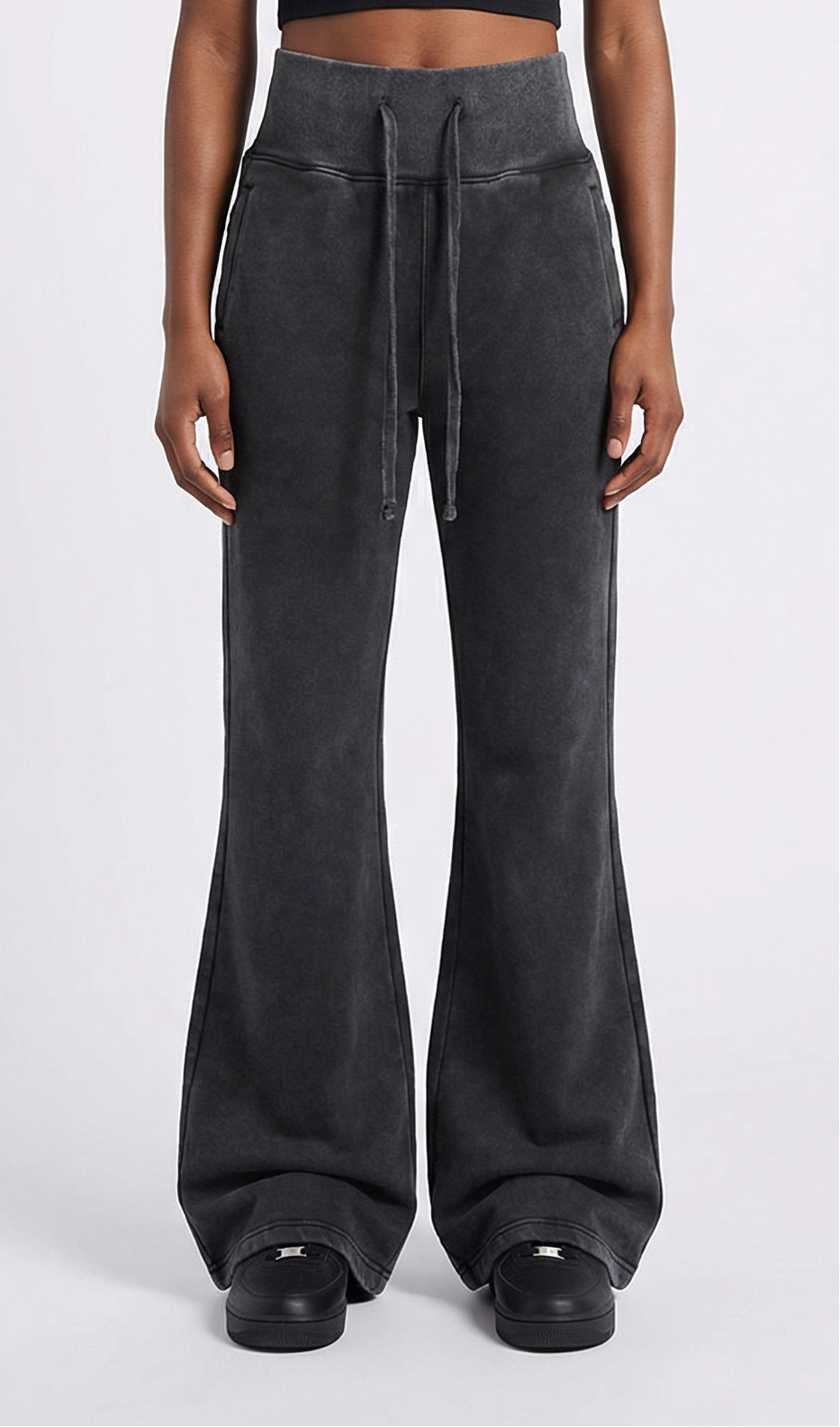 Person wearing dark black high-waisted pants on a white background