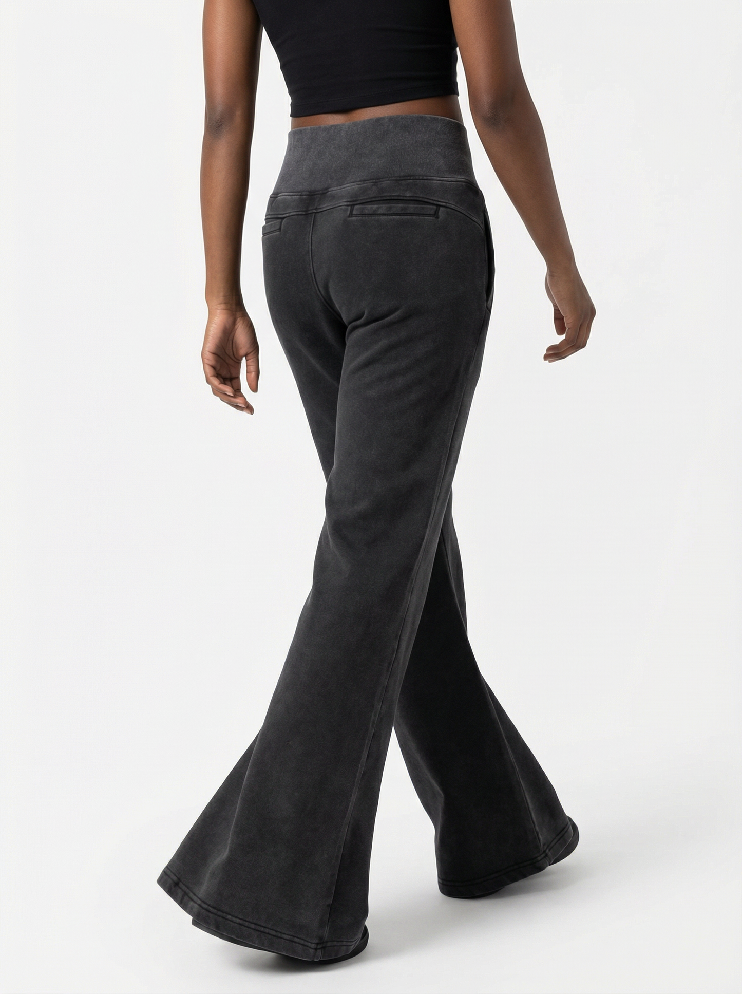 Black flared pants worn by a person on a white background